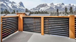 A balcony with a view of snow-capped mountains and pine trees. - Spring Creek Vacations 3 BR Premier Condo 309W (Canmore)
