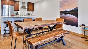 Une cuisine moderne avec des meubles en bois, un réfrigérateur en acier inoxydable et un coin repas comprenant une table et des chaises en bois.