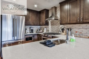 Una cocina moderna con electrodomésticos de acero inoxidable, gabinetes de madera oscura y un salpicadero de azulejos.