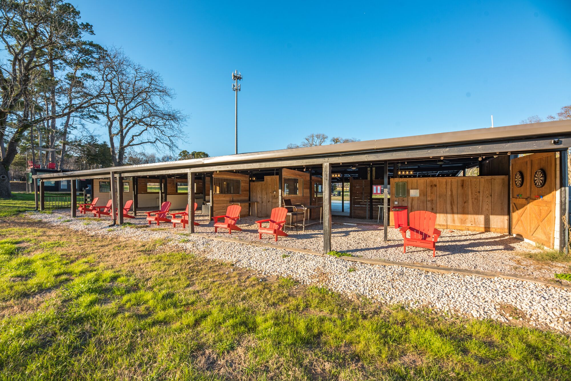Un espace extérieur abrité, aménagé avec des chaises rouges et une structure en bois.