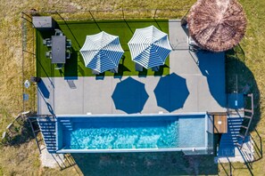 An aerial view of a pool area with a large pool, two umbrellas, and a pergola. - Pit Master: 2 mins to Lake Conroe! Heated Pool, Fire Pit, Stocked Ponds (Willis)
