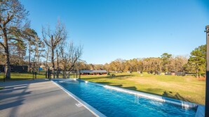 A swimming pool with a paved deck, surrounded by trees and a grassy area. - Good Smoke -2 mins to Lake Conroe! Rooftop deck, Heated Pool, Fire Pit (Willis)