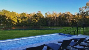 A swimming pool with a view of a grassy area and trees. - Applewood: 2 mins to Lake Conroe! Rooftop deck, Heated Pool, Fire Pit (Willis)