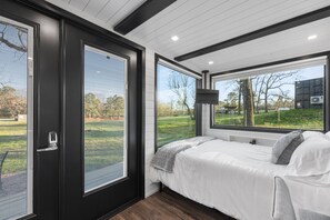 Relax in a serene space with a large bed and a view of the lush outdoor area.