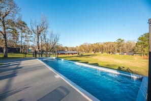 Relax by the serene pool surrounded by lush trees and a well-manicured lawn.
