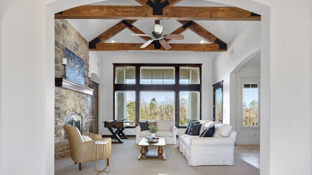 A spacious living room with a fireplace, large windows, and a vaulted ceiling. - LUXURY home 2 mins to Lake Conroe! Heated Pool, Stocked Ponds, Cute Pygmy Goats (Willis)