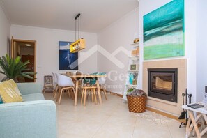 A modern living room with a dining area, a fireplace, and a large abstract painting on the wall.
