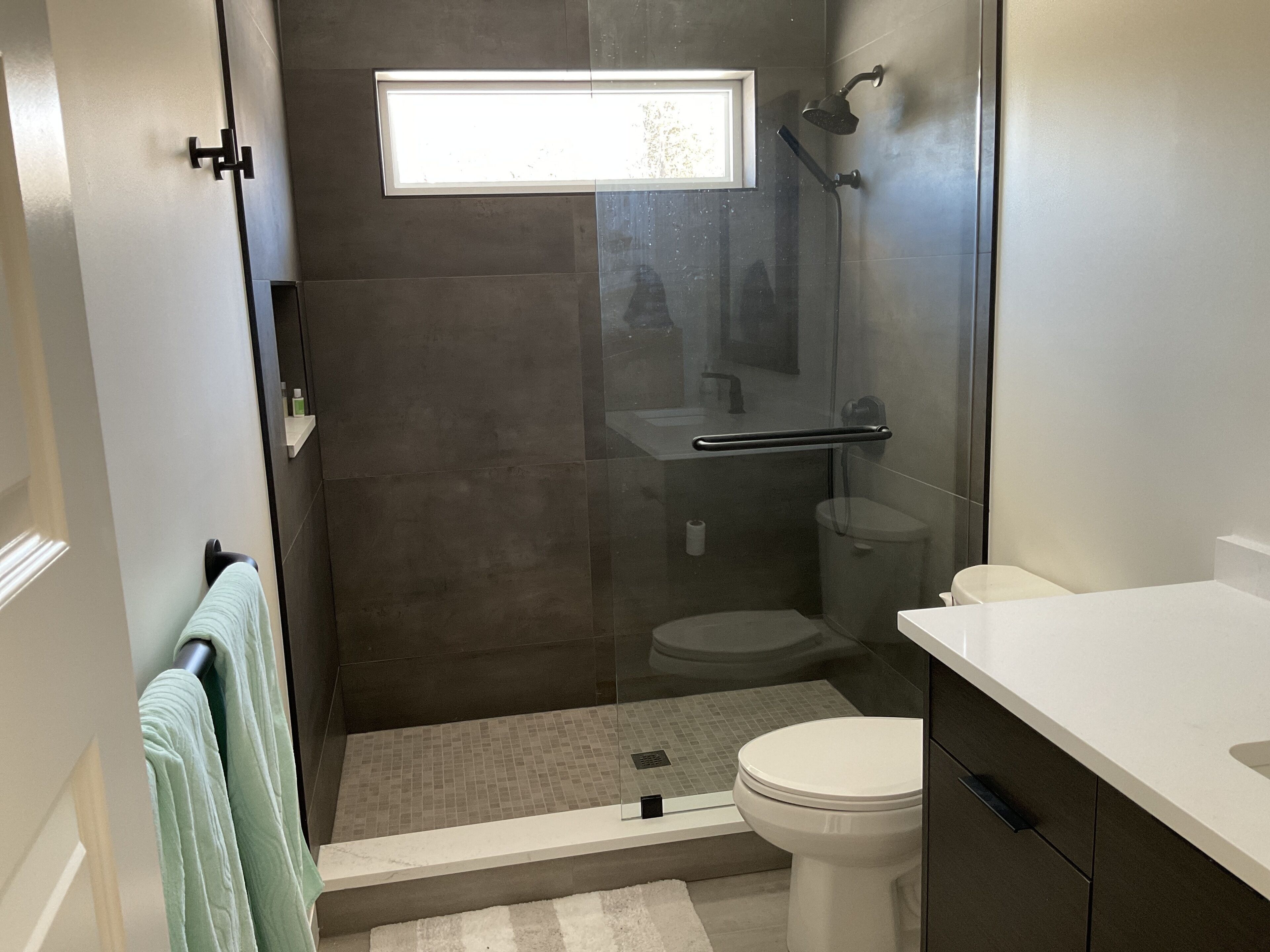 A modern bathroom with a glass-enclosed shower, a toilet, and a sink.