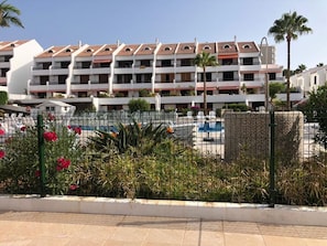 Un hôtel doté de nombreux balcons, d’une piscine et d’un jardin clos.