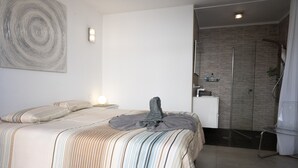 A modern bedroom with a large bed, a shower area, and a minimalist design.