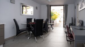 A dining area with a table and chairs, a ceiling fan, and a view of the outdoors.