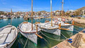 A marina with several boats docked, a clear sky, and buildings in the background. - Samoter, Finca 5EstrellasHome Mallorca (Cala San Vicente)