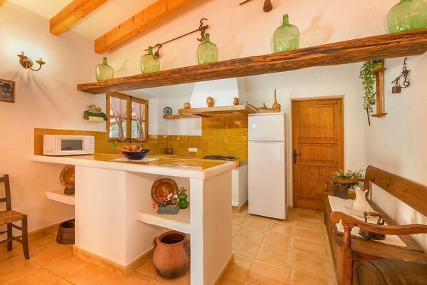 A kitchen with a central island, white appliances, and a wooden bench. - Pedreta, Finca 5StarsHome Mallorca (Alcúdia)