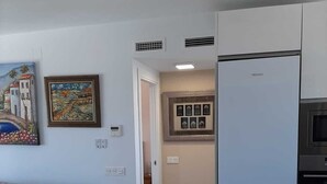 A modern kitchen with a built-in refrigerator, a dining area with a table and chairs, and a living room with a sofa. - Beautiful apartment with pool (Torremolinos)