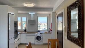 A compact kitchen with a washing machine, a dining table, and a large mirror. - Beautiful apartment with pool (Torremolinos)