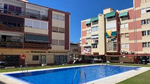 A swimming pool surrounded by a building with balconies and a flat roof. - Beautiful apartment with pool (Torremolinos)