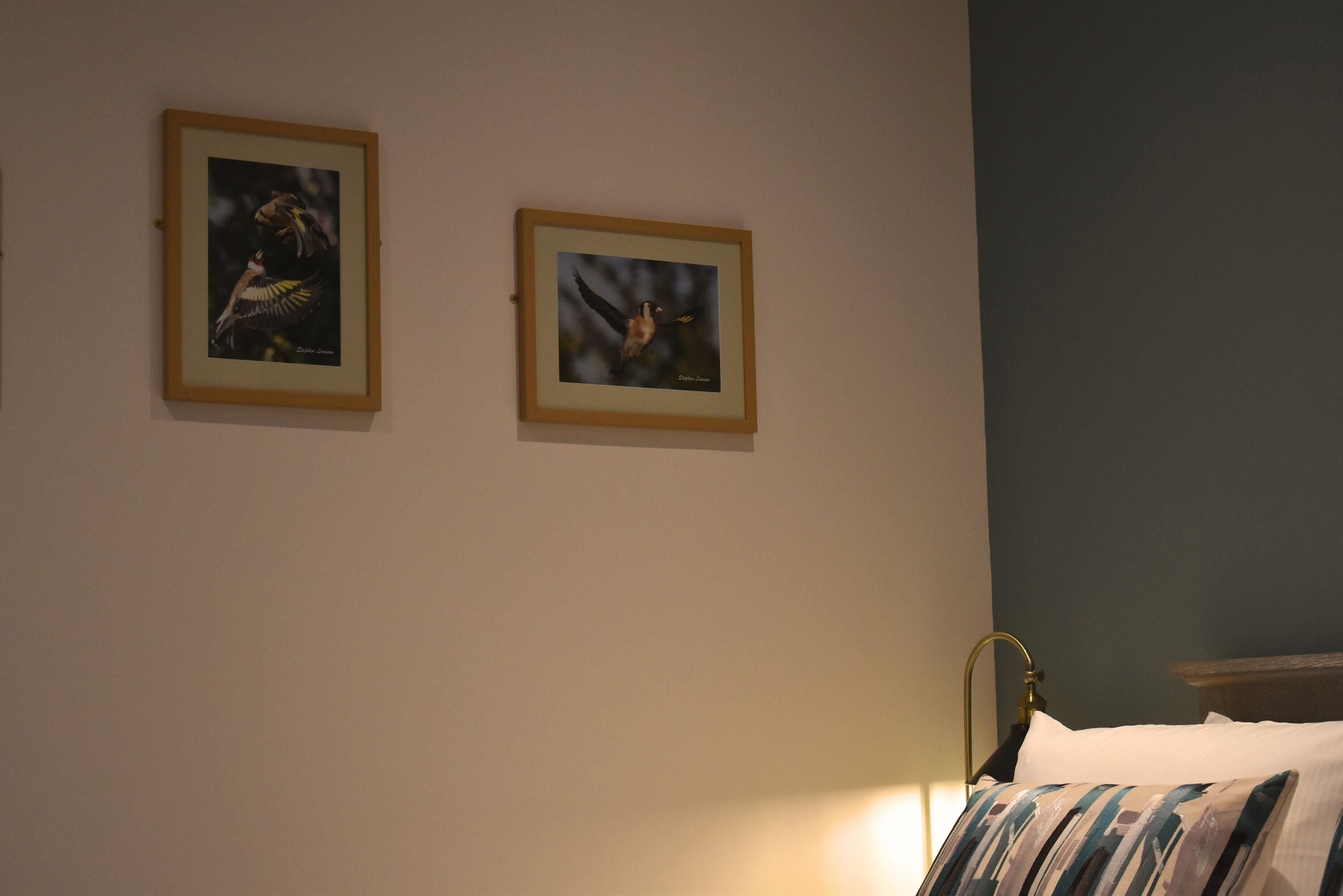Une chambre à coucher avec un lit, une table de chevet et deux tableaux encadrés accrochés au mur.