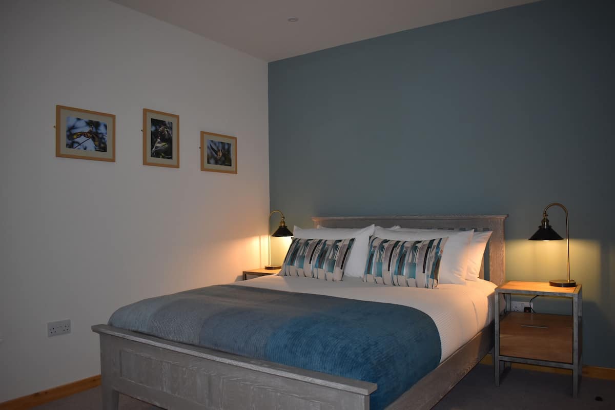 A bedroom with a bed, two bedside tables, and three framed pictures on the wall.