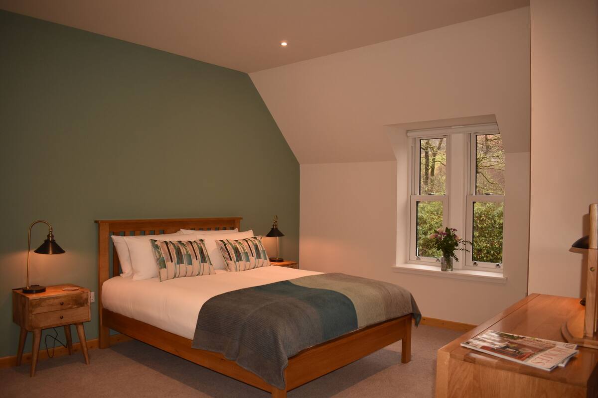 A bedroom with a bed, bedside tables, a window with a view, and a nightstand.