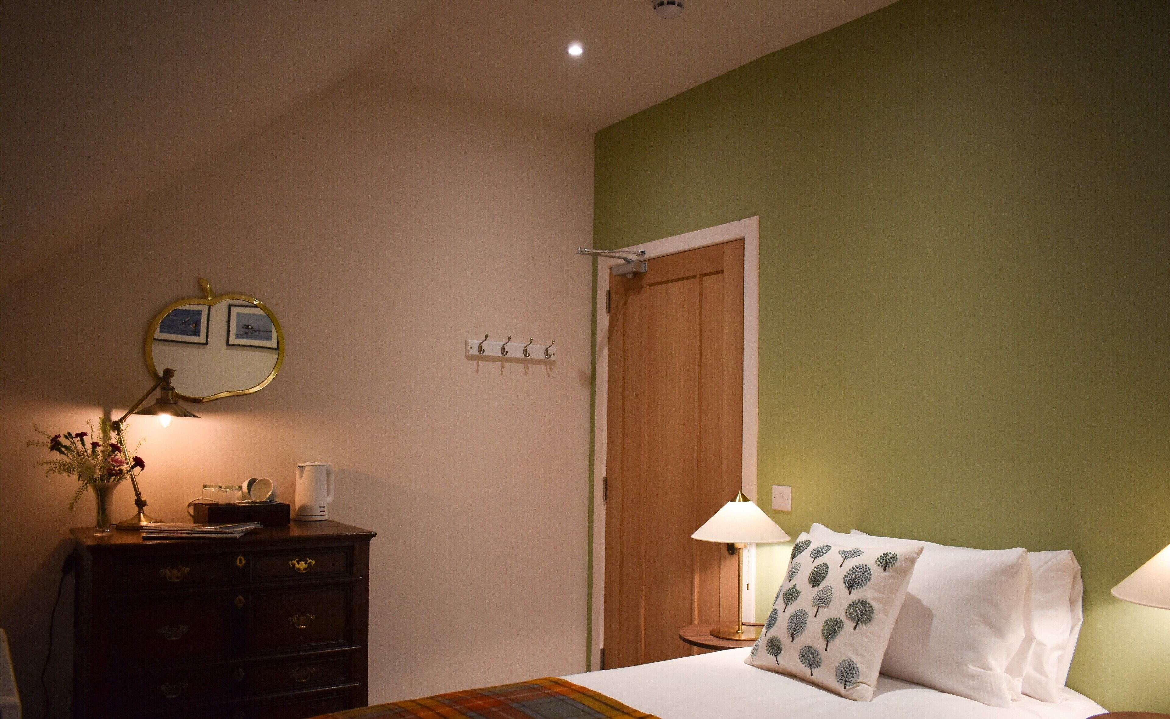 A bedroom with a bed, a dresser, a mirror, and a door.