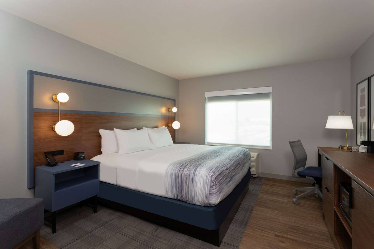 A modern hotel room with a large bed, bedside tables, a desk, and a chair.