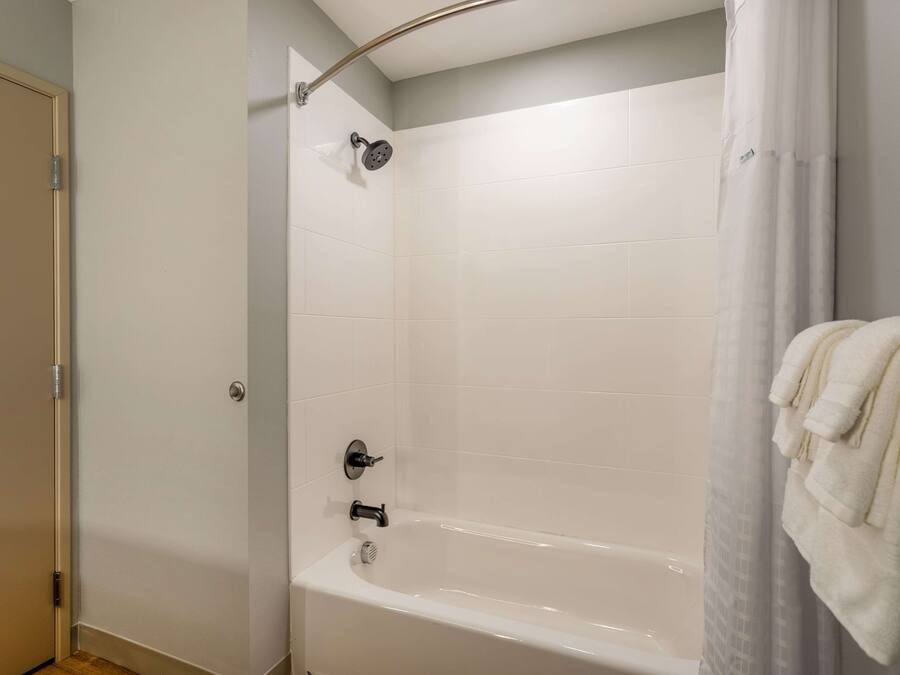 Un baño con una bañera, un cabezal de ducha y un perchero para toallas.