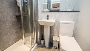 Une salle de bain moderne avec une douche à parois de verre, un lavabo sur colonne et des toilettes.