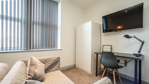 Une chambre à coucher comprenant un lit, un bureau, une chaise, une télévision et une armoire.