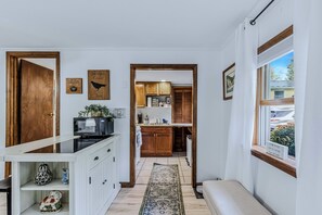 A narrow hallway leading to a kitchen with wooden cabinets, a built-in microwave, and a coffee machine. - Vermont Retreat (Bridgewater)