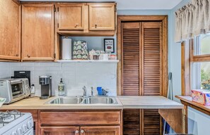 A kitchen with wooden cabinets, a built-in coffee maker, a toaster, and a sink. - Vermont Retreat (Bridgewater)