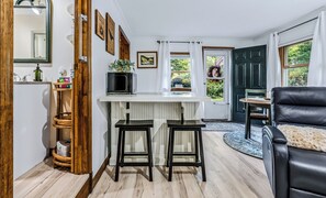Une cuisine avec un plan de travail blanc, deux tabourets, un four à micro-ondes et un meuble en bois.