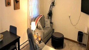 A living room with a sofa, a dining table, a coffee table, a ceiling fan, and a TV mounted on the wall. - Vermont Retreat (Bridgewater)