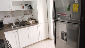 Eine Küche mit weißen Schränken, einem Edelstahlkühlschrank und einer Granitarbeitsplatte.