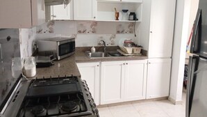 Eine Küche mit weißen Schränken, einem Gasherd, einer Mikrowelle und einem Spülbecken.