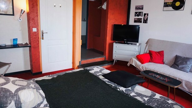 A bedroom with a bed, a TV, a sofa, and a desk. - Artists Room - Up to 3 people (no pets) (Messey-sur-Grosne)