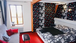 A bedroom with a bed, a sofa, a small table, and a window. - Artists Room - Up to 3 people (no pets) (Messey-sur-Grosne)