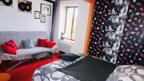 A room with a bed, a sofa, a small table, and a window. - Artists Room - Up to 3 people (no pets) (Messey-sur-Grosne)