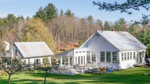 A white two-story house with a covered porch, large windows, and a small deck. - Absolutely Gorgeous Vermont Garden Cottage (Montpelier)