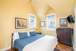 A bedroom with a bed, a dresser, and two windows.