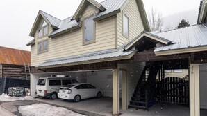 Ein zweistöckiges Haus mit Garage, einem Lieferwagen und einem Auto vor der Tür.