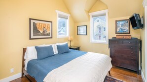 A bedroom with a large bed, two windows, a dresser, and a TV mounted on the wall. - Charming Downtown Telluride Retreat | Walk to Main Street, Gondola & Lift 7 (Telluride)