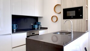 A modern kitchen with a built-in microwave, stainless steel sink, and a coffee maker. - Apartment with River View, Tavira (Tavira)