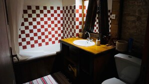 Een badkamer met een wand betegeld met ruitjes, een houten wastafelmeubel met een wastafel, een spiegel en een toilet.