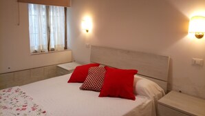 Een slaapkamer met een bed, twee nachtkastjes, een raam met gordijnen en wandlampen.