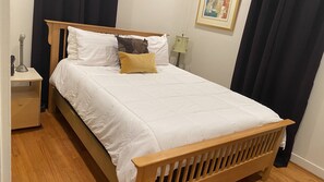 A neatly made bed with a wooden headboard, a bedside table with a lamp, and a framed picture on the wall. - Cute, cozy rancher close to down town Annapolis (Annapolis)