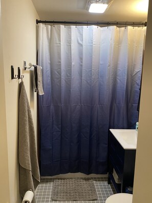 A bathroom with a shower curtain, a towel rack with towels, a sink, and a toilet. - Cute, cozy rancher close to down town Annapolis (Annapolis)