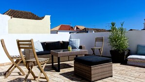 An outdoor patio with wicker furniture, a potted plant, and a view of the cityscape.