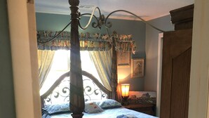 Een slaapkamer met een hemelbed, een nachtkastje en een lamp.