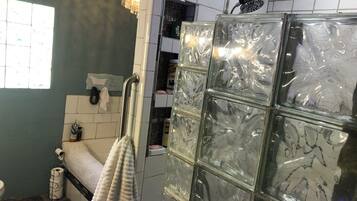 Un baño con cabina de ducha de vidrio, inodoro, lavamanos y toallero.