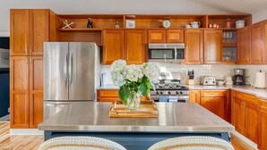 Una cocina moderna con armarios de madera, electrodomésticos de acero inoxidable y una isla central con un jarrón de flores.